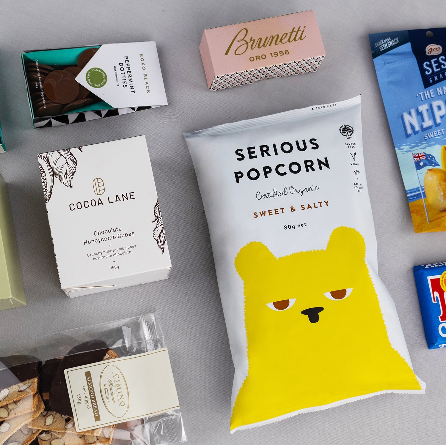 Deluxe snack hamper with sweet and salty Serious Popcorn, pink Brunetti box, Cocoa Lane chocolate, and assorted gourmet.