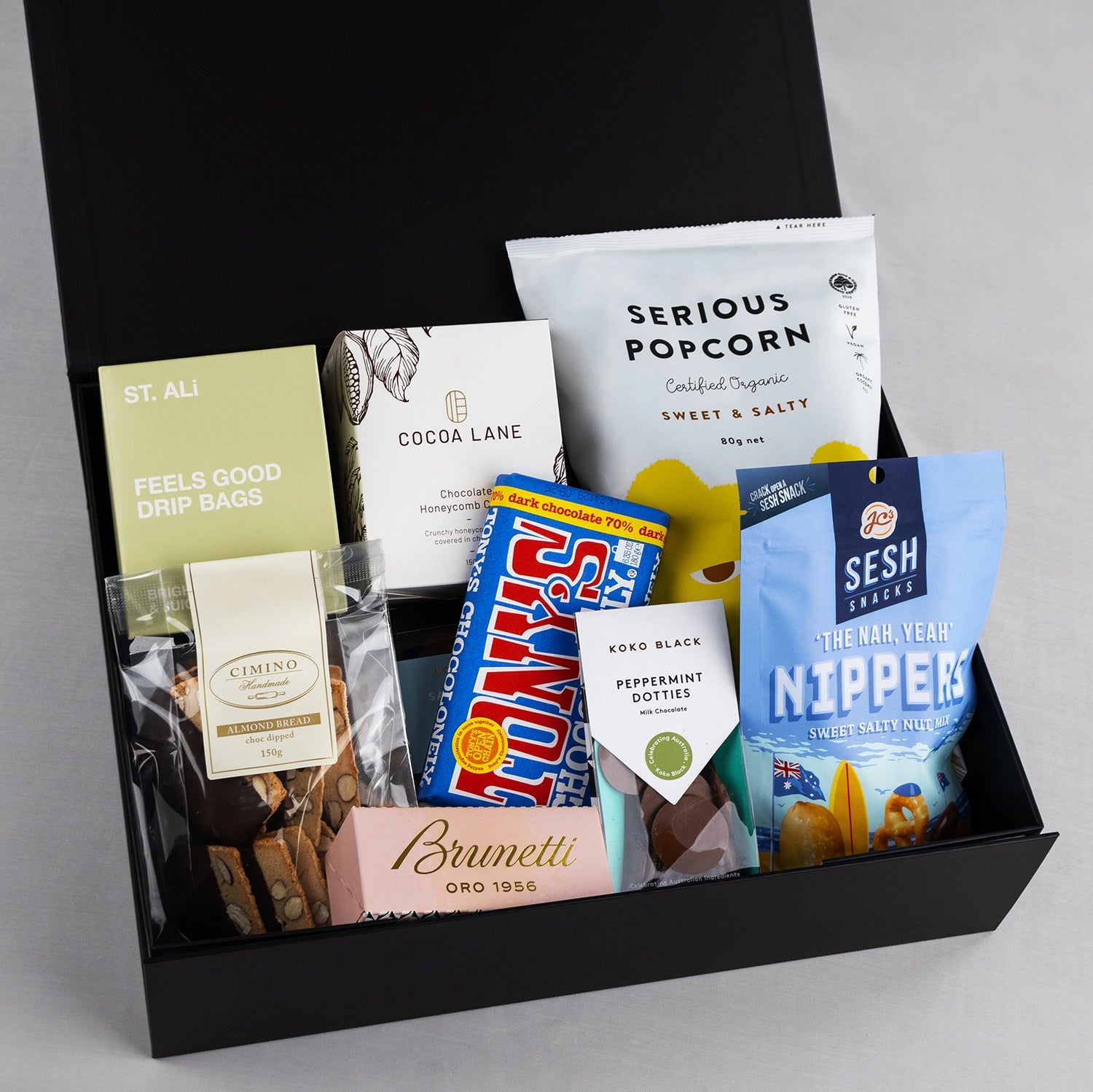 Black deluxe snack hamper box with assorted gourmet snacks including Serious Popcorn, Sesh Chips, Brunetti chocolates, and.