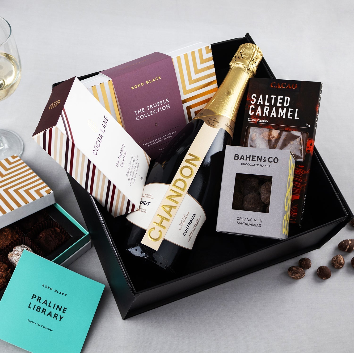 Black gift hamper with Chandon sparkling wine bottle, salted caramel chocolate, praline logan bar, and Bahen & Co dark.