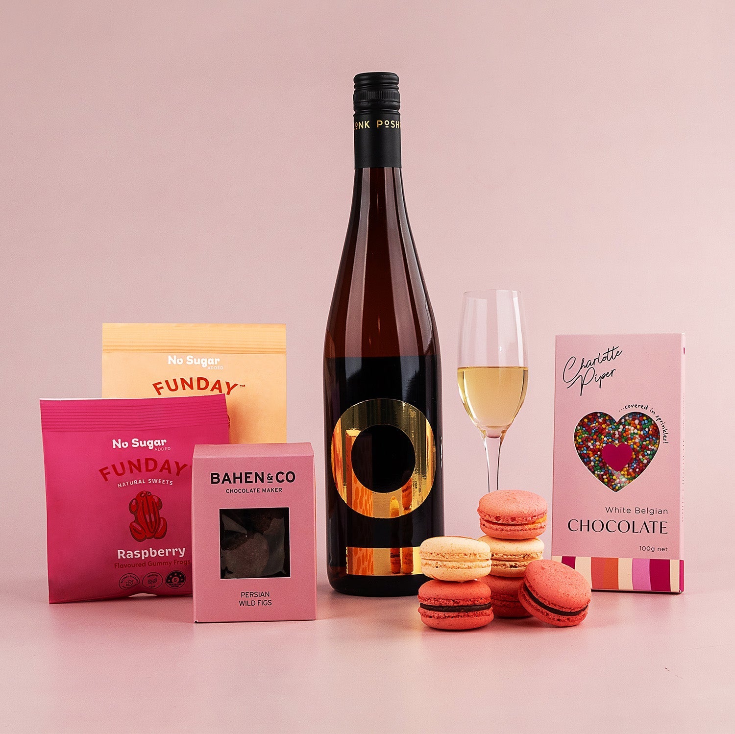 Posh Plonk Pinot Grigio bottle with six orange and yellow macarons, pink raspberry fudge box, chocolate bar with heart.