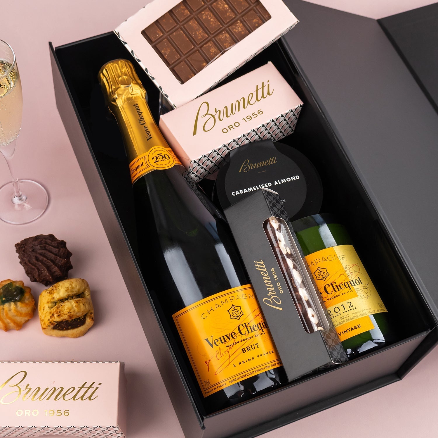 Veuve Clicquot champagne bottle with Brunetti chocolate, cheese cracker jar, and corkscrew in black gift box.